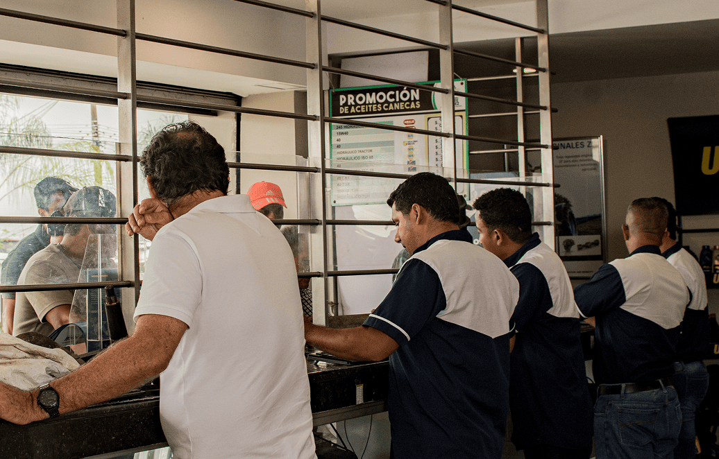 Equipo de asesoramiento técnico mostrando repuestos y componentes a clientes en tienda